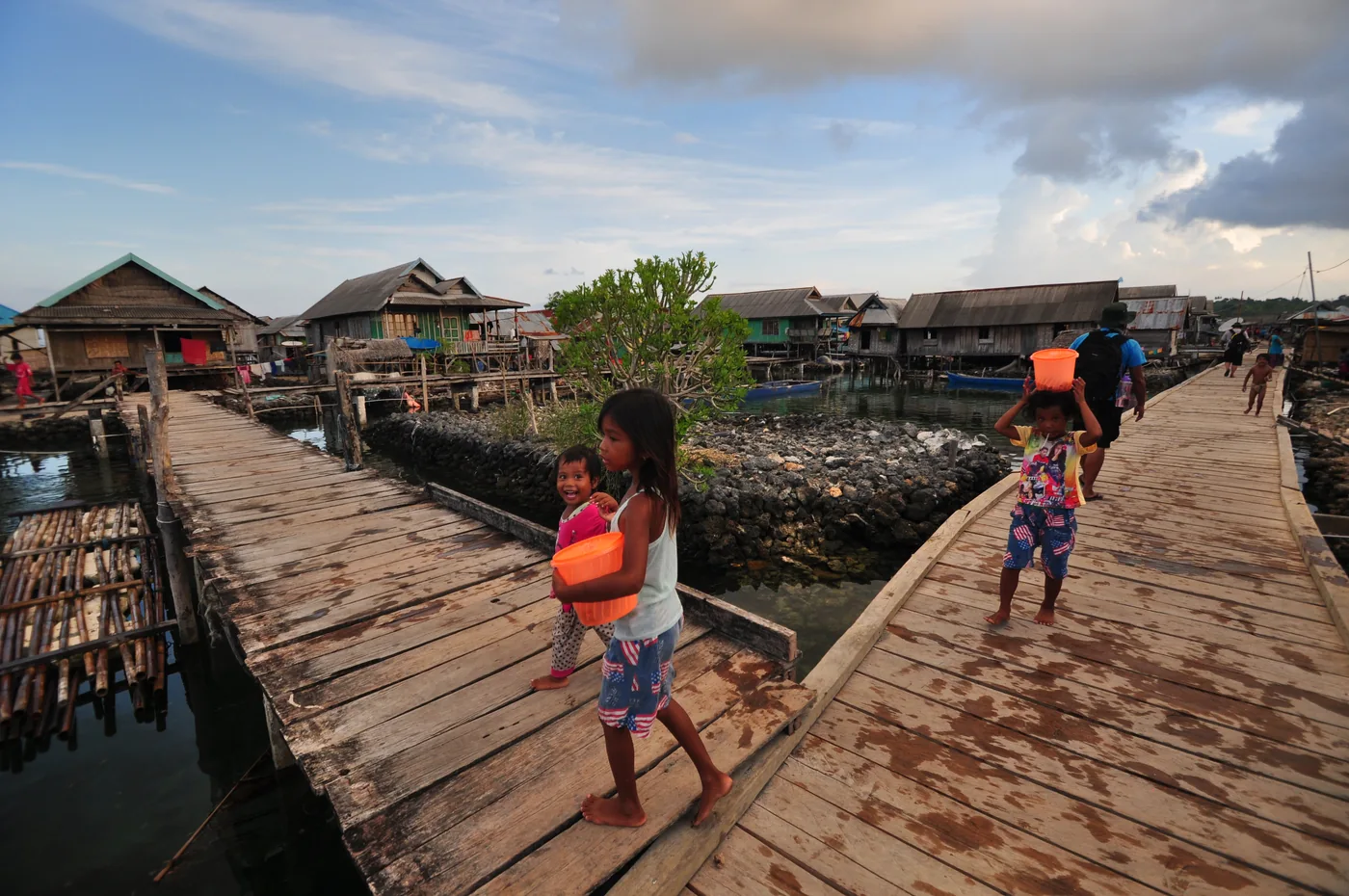 Warga berjalan di jembatan kayu di antara rumah-rumah Desa Bajo Sampela, Wakatobi.